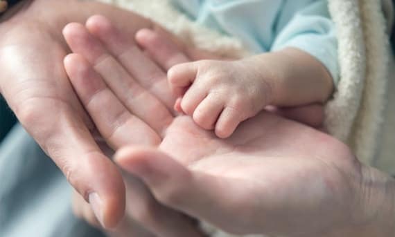 Parents holding newborn's hand, secure about their future with Citigold